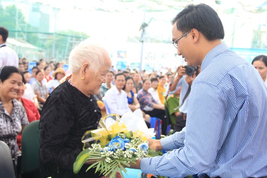 Ông Bùi Gia Hiếu, Hiệu trưởng Trường THPT Nhân Việt, tặng hoa 
cho mẹ Việt Nam anh hùng Trần Thị Cách Ảnh: ĐẶNG TRINH
