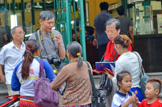 Người bán hàng rong chèo kéo du khách mua hàng lưu niệm trước Bưu điện TP HCM Ảnh: TẤN THẠNH