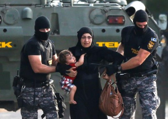 Cảnh sát Hungary áp giải người tị nạn. Ảnh: Reuters