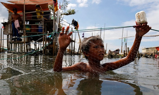Một cậu bé người Philippines đang giữ lưới đánh cá tại một ngôi làng ven biển ở thành phố Malabon, phía Đông Manila, trong khi Melor tiếp tục hướng về miền Trung Philippines. Ảnh: EPA