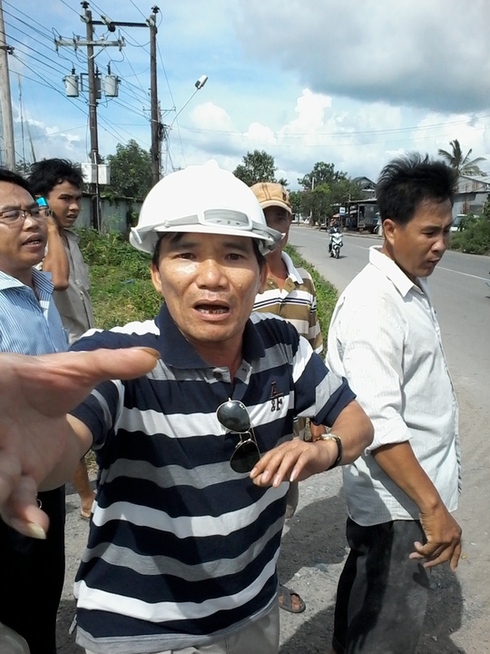 
Ông Thanh (đeo kính trắng, mặc áo sọc phía sau, bìa trái) xúi giục ông Long giật máy ảnh và đấm vào mặt phóng viên
