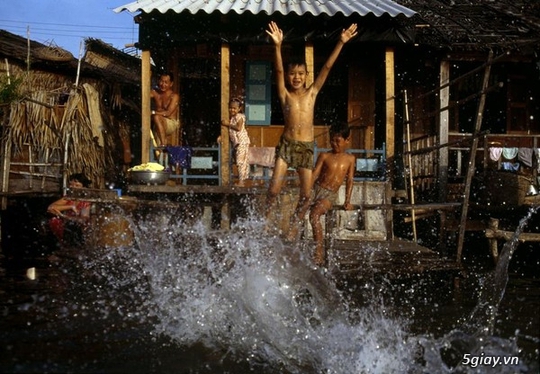 
Lũ trẻ vui đùa dưới làn nước mát phía trước một nhà nổi.
