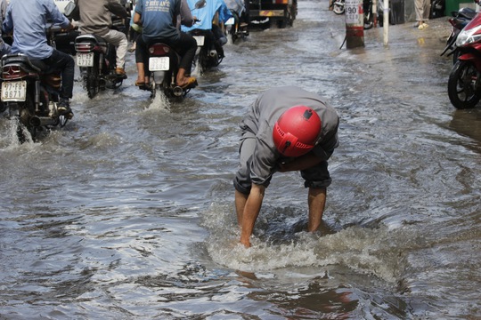 
 Một người dân đang túc trực tại một ống cống để khơi thông dòng nước và nhắc nhở người đi đường
