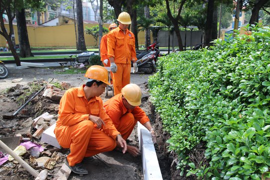 Anh Tạ Văn Trung - tổ trưởng tổ sản xuất Công ty Dịch vụ công ích quận 5, TP HCM (hàng đầu, bìa trái) - hướng dẫn đồng nghiệp chăm sóc cây cảnh