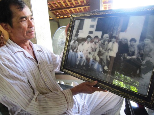 Ông Nguyễn Văn Hòa bên bức ảnh thời thiếu niên ra Bắc gặp Bác Hồ