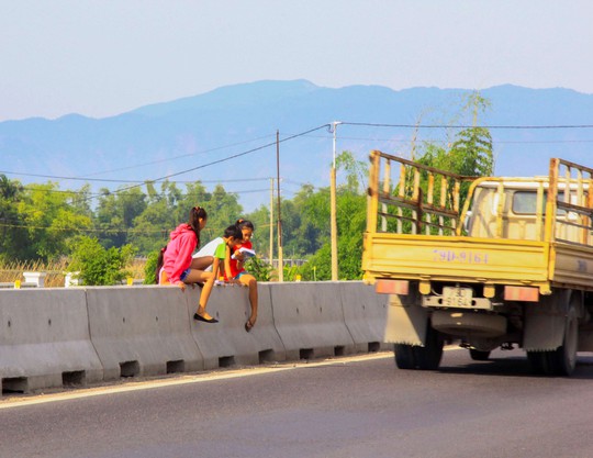 Một nhóm học sinh ở xã Ninh Ích, thị xã Ninh Hòa, tỉnh Khánh Hòa trèo qua dải phân cách để về nhà Ảnh: KỲ NAM