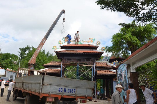 Xe cẩu được huy động cùng hàng chục công nhân để tháo dỡ các vật liệu làm cổng chính