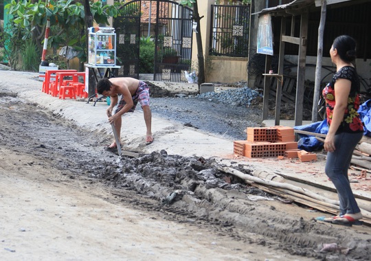 Người dân trên đường Dương Đình Cúc phải dọn bùn do xe tải chở đất, cát rơi xuống đường