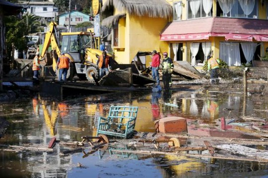 Người dân dọn dẹp đống đổ nát do động đất và sóng thần gây ra ở TP Concon. Ảnh: Reuters