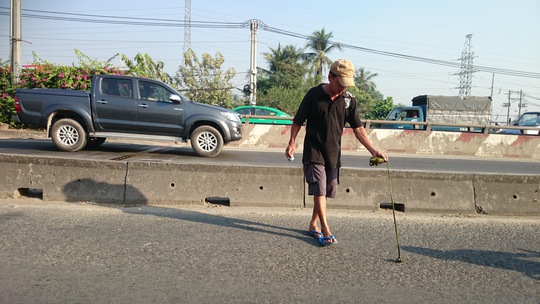 
Nhặt tay không xuể, một người đàn ông khác sử dụng dây buộc nam châm để nhặt đinh nhanh hơn.
