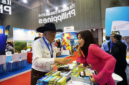 Khách nước ngoài lấy ấn phẩm quảng bá du lịch Việt Nam tại hội chợ du lịch - Ảnh: Đào Loan
