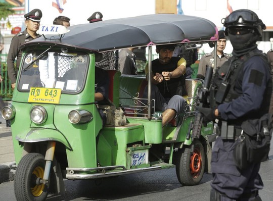 Police officers escort a key suspect in last months Bangkok bombing, yellow shirt, identified by Thai police as Yusufu Mieraili, traveling on a Chinese passport, sits on a three wheel taxi outside Hua Lamphong railway station during a re-enactment for the 17 August bombing at Bangkoks popular Erawan Shrine that left 20 people dead and more than 120 injured, Wednesday, 9 September 2015