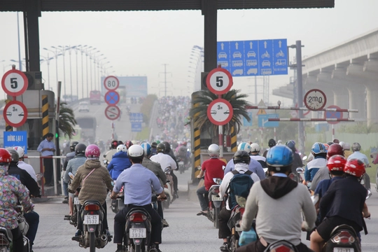 
Xe máy ken đặc, chen chúc lưu thông trên cầu Rạch Chiếc. Dòng xe máy tiếp tục lưu thông thành dòng lớn tràn qua làn đường xe bốn bánh.
