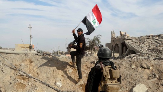 
Một thành viên lực lượng an ninh Iraq cầm quốc kỳ tại TP Ramadi hôm 27-12Ảnh: REUTERS
