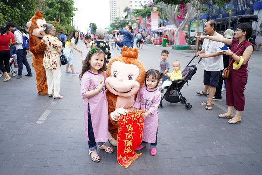 Trẻ em chụp ảnh lưu niệm với các chú khỉ ở đường hoa Nguyễn Huệ