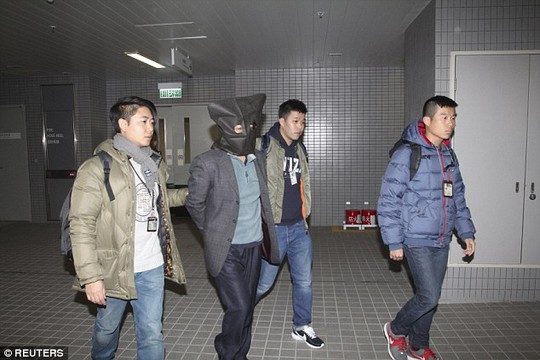Ông Shi (trùm đầu) bị cảnh sát bắt khi vừa đáp máy bay xuống sân bay Hồng Kông. Ảnh: Reuters