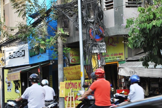 Biển báo tại giao lộ Trần Phú - Trần Bình Trọng (quận 5) bị trụ điện bao vây.