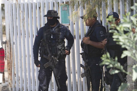 Cảnh sát tiểu bang Mexico đứng gác gần lối vào Rancho del Sol, nơi diễn ra vụ sát hại 22 dân thường. Ảnh: AP