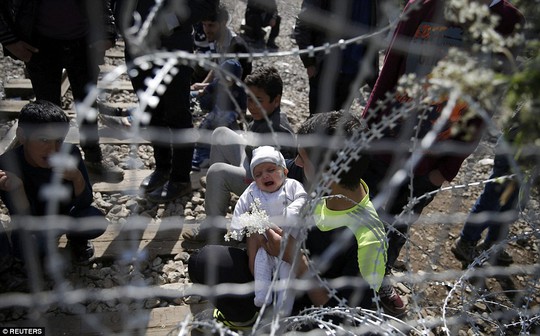 
Một người đàn ông bế đứa con đang khóc với hy vọng những người gác cổng có thể mủi lòng. Ảnh: Reuters
