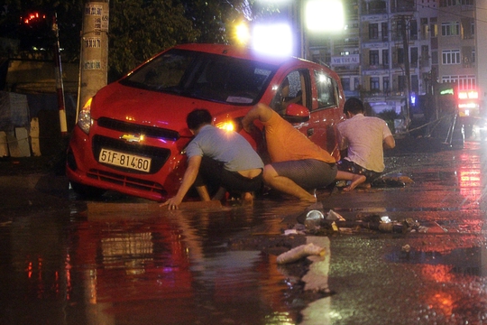 Một nhóm thanh niên khác đang cố giải cứu một chiếc ô tô bị sa phải cống nước ngập đang thi công trên đường Trần Não (quận 2). Khoảng 30 phút sau chiếc xe mới được giải cứu thành công.