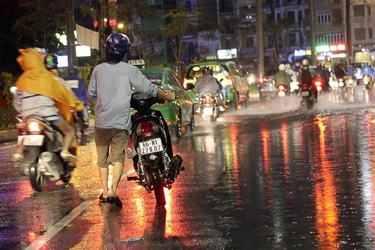 Một nữ thanh niên dắt chết xe chết máy sau khi cố vượt qua vùng nước ngập trên đường Trần Não (quận 2).