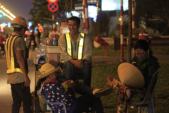 
Hai người thợ tranh thủ nghỉ ngơi, trò chuyện với những người bán nước trước khi tăng ca vào ban đêm.
