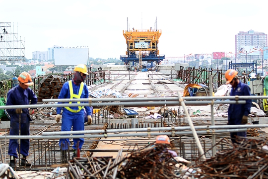 Các công nhân đang tất bật thi công các hạng mục tại nhà ga ngã tư Bình Thái. Phía xa, hệ thống đà giáo di động đã lắp ghép kết nối các nhịp cầu vào nhà ga ngã tư Bình Thái.