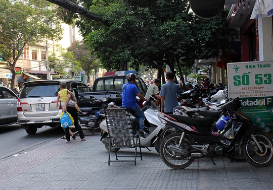 
Một người phụ nữ mang theo hai con nhỏ buộc phải di chuyển ra lòng đường để đi vì vỉa hè và lề đường trước cửa công an Phường (phường 17, quận Bình Thạnh) không còn kẽ hở nào.
