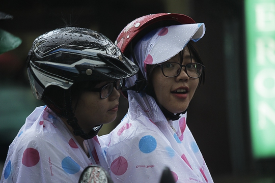 
Hai cô gái trẻ tấp xe vào lề đường, tranh thủ trò chuyện với nhau chờ cơn mưa dứt.
