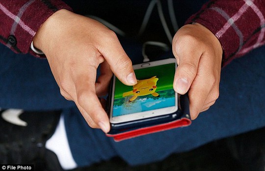 
Người chơi dùng điện thoại thông minh săn bắt Pokemon ở các địa điểm ngoài đời thực. Ảnh: Daily Mail
