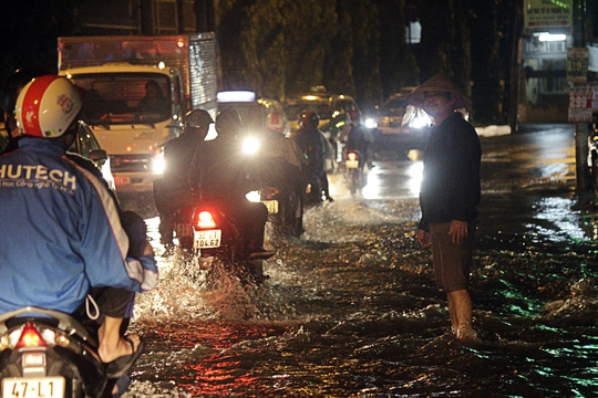 Cơn mưa lớn chiều tối 26-8, khiến nhiều nơi tại TP HCM ngập nặng, tràn vào nhà người dân khiến cuộc sống sinh hoạt thường ngày đảo lộn. Trong ảnh: Một người đàn ông đang đứng cảnh báo người đi đường không đi vào vùng nước xoáy cuốn nguy hiểm.