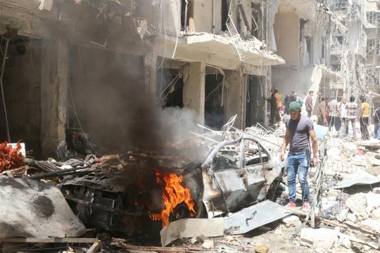 Lửa cháy âm ỉ sau các cuộc không kích vào Bustan al-Qasr ở Aleppo hôm 28-4. Ảnh: REUTERS