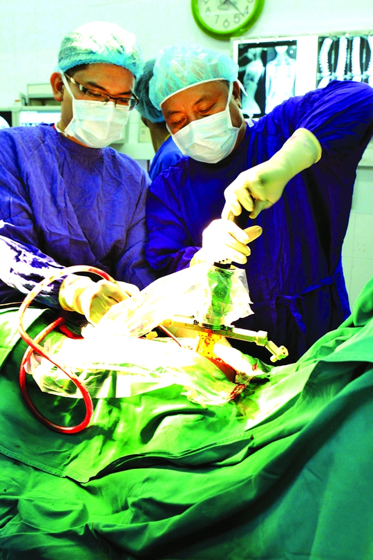 
PGS-TS Nguyễn Văn Thạch (phải) trong một ca phẫu thuật cho bệnh nhân bị bệnh cột sống
