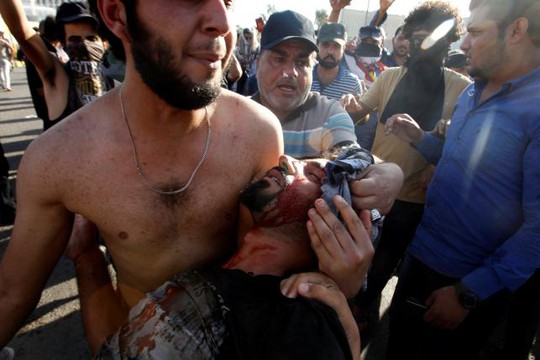 
Một người biểu tình chống chính phủ Iraq ôm một người biểu tình bị thương trong vụ bạo loạn ở Vùng Xanh hôm 20-5. Ảnh: Reuters
