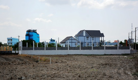 Một căn biệt thư đã hoàn thành, kế bên là một móng nhà đang xây dựng nằm trên đất ruộng tại ấp 4, xã Đa Phước, huyện Bình Chánh. Ảnh chụp trưa 11-5 Ảnh: MINH THANH