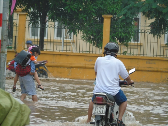 
Một người đàn ông đã phải dựng xe bên lề đường để cõng con gái đến trường Tiểu học Nam Trung Yên, quận Cầu Giấy cho kịp giờ học.
