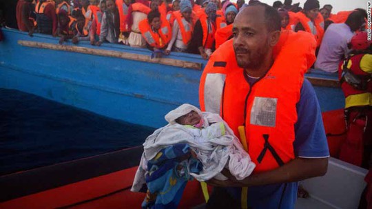 Một người đàn ông chạy khỏi Libya bế đứa con 5 ngày tuổi sau khi được giải cứu hôm 29-8 Ảnh: AP