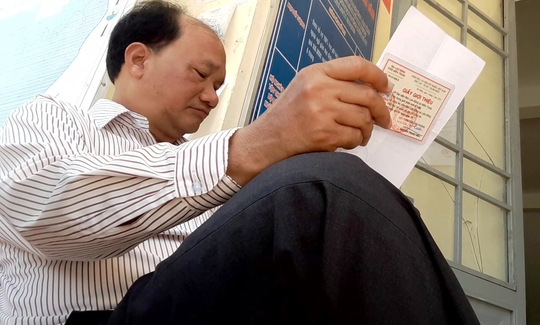 Ông K’ Xuân Riêng vừa kiểm tra giấy giới thiệu của phóng viên, vừa gọi điện thoại