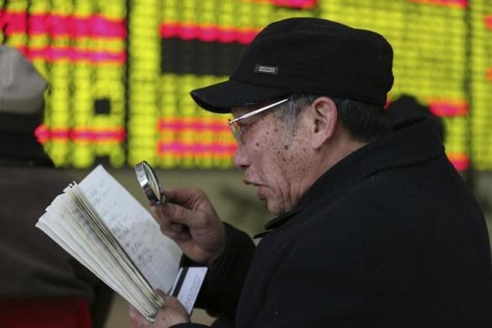 Một nhà đầu tư Trung Quốc đọc sổ ghi chép hôm 5-1 ở tỉnh Giang Tô. Ảnh: REUTERS