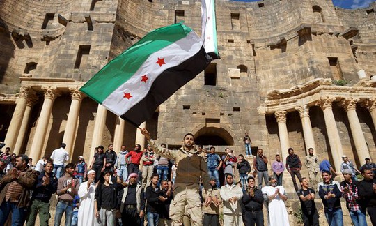 
Một người biểu tình giương cao lá cờ của phe nổi dậy tại TP Bosra al-Sham – Syria hôm 4-3. Ảnh: REUTERS
