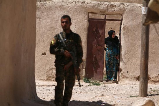 
Một thành viên của SDF đứng gần một phụ nữ ở TP Manbij. Ảnh: REUTERS
