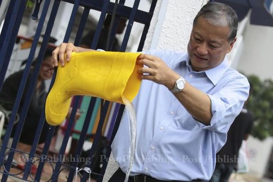 Ông MR Sukhumbhand Paribatra trút nước khỏi ủng cao su. Ảnh: Bangkok Post