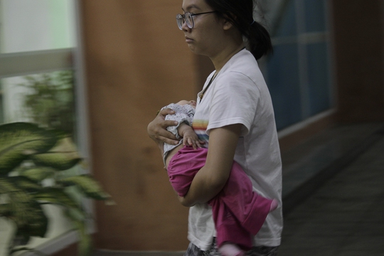 Một người mẹ ôm con lo lắng, mệt mỏi vì chờ tàu quá lâu ở ga Biên Hòa.