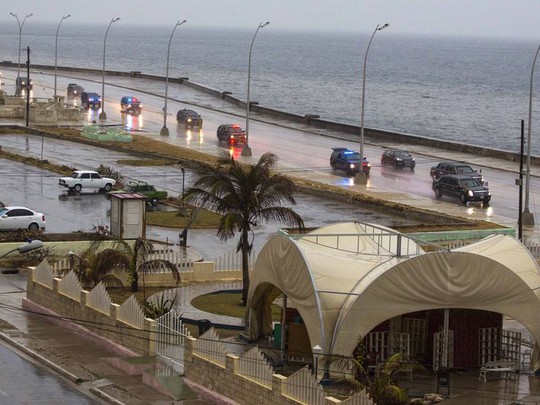 Đoàn xe chở Tổng thống Obama và gia đình xuyên màn mưa chạy dọc con đê biển Malecon ở Havana. Ảnh: AP