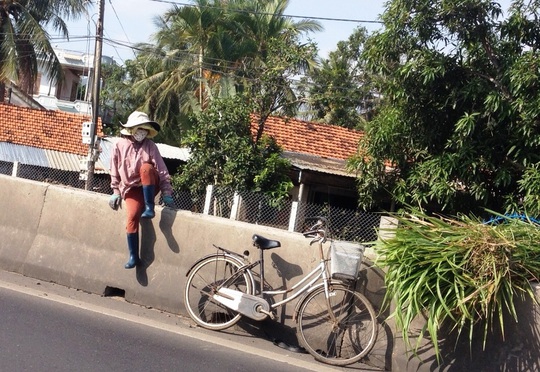 Qua bên đường, chị phụ nữ phân bua: Nhà chỉ cách vài bước chân nhưng để khỏi phải đạp xe đi vòng hơn 1 cây số nên mới liều vậy - Ảnh: Hồng Ánh