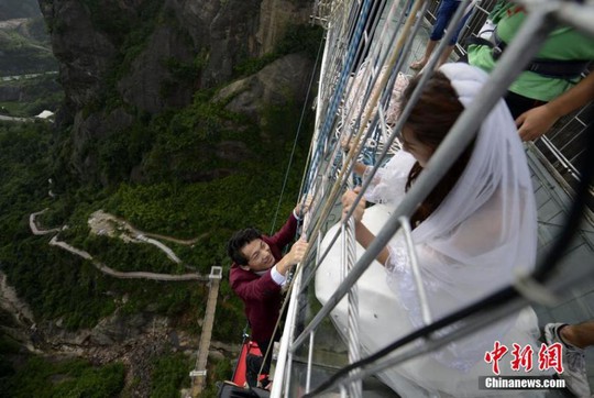 
Chú rể, cô dâu từ từ leo xuống tấm thảm đỏ được treo lơ lửng ở độ cao 180 mét. Ảnh Chinanews
