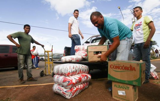 
Một người đàn ông đưa hàng hoá lên xe chuẩn bị hành trình trở về Venezuela. Ảnh: Reuters
