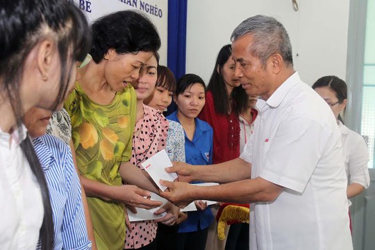 Ông Đặng Ngọc Tùng, nguyên Chủ tịch Tổng LĐLĐ Việt Nam, trao quá cho công nhân khó khăn tại huyện Nhà Bè Ảnh: HOÀNG TRIỀU