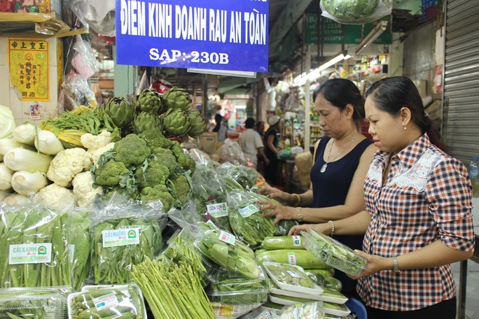 
Chị Nguyễn Thị Huyền Trân (bìa phải) kiểm tra một điểm kinh doanh rau sạch
