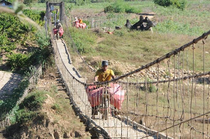 
Những người đi xe máy qua cầu treo tạm tại làng Tà Poóc, cách điểm đặt dây cáp chưa đầy 1 km

